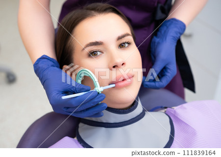 Process of preparation of patient before dental X-ray procedure. Woman instructs patient on how to tilt head before dental X-ray procedure Process of preparation of patient before dental X-ray procedure. Woman instructs patient on how to tilt head before dental X-ray procedure 111839164