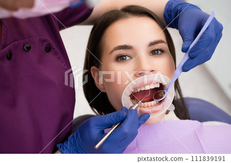 Female dentist blows air across teeth drying surface from saliva for further checkup. Dentist prepares for dental examination of oral cavity 111839191