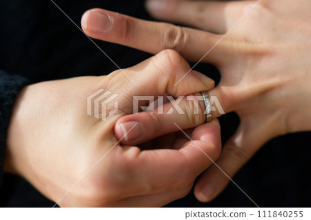 Hand of a woman in her 40s removing a ring 111840255