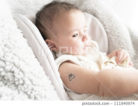 A 6-month-old baby boy with a bandage on his right arm for the injection site A 6-month-old baby boy with a bandage on his right arm for the injection site 111840974