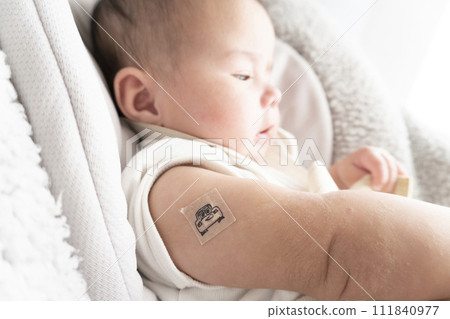 一名 6 個月大的男嬰，右臂上綁著繃帶用於注射部位 111840977