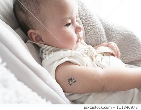 A 6-month-old baby boy with a bandage on his right arm for the injection site 111840978