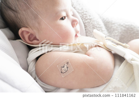 一名 6 個月大的男嬰,右臂上綁著繃帶用於注射部位 一名 6 個月大的男嬰,右臂上綁著繃帶用於注射部位 111841162
