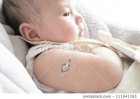 一名 6 個月大的男嬰,右臂上綁著繃帶用於注射部位 一名 6 個月大的男嬰,右臂上綁著繃帶用於注射部位 111841163