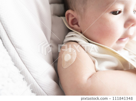 A 6-month-old baby boy with a bandage on his right arm for the injection site 111841348