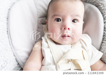 A 6-month-old baby boy with a bandage on his right arm for the injection site 111841349