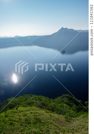The sun is reflected on the lake surface The sun is reflected on the lake surface 111841562