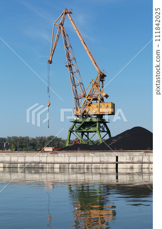 Portal crane stands on the river coast in Bulgarian port on a sunny summer day 111842025
