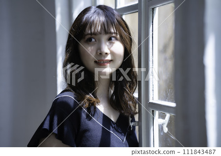 A woman relaxing by the window A woman relaxing by the window 111843487