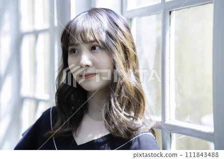 A woman relaxing by the window A woman relaxing by the window 111843488