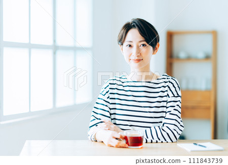 A middle-aged woman taking a break in the living room. 111843739