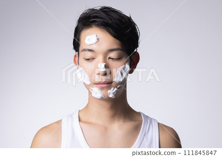 Portrait of a man washing his face and doing skin care on a white background 111845847