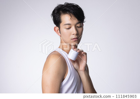 Image of a man with a white background holding cosmetics and skin care goods 111845903