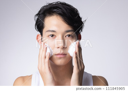 Portrait of a man washing his face and doing skin care on a white background 111845905