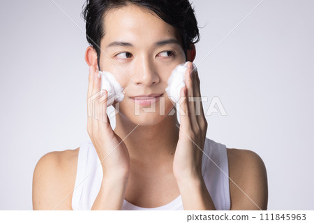Portrait of a man washing his face and doing skin care on a white background 111845963