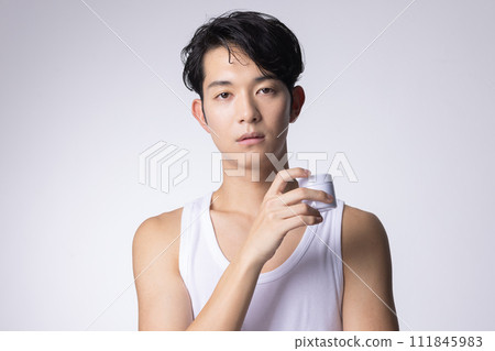 Image of a man with a white background holding cosmetics and skin care goods 111845983