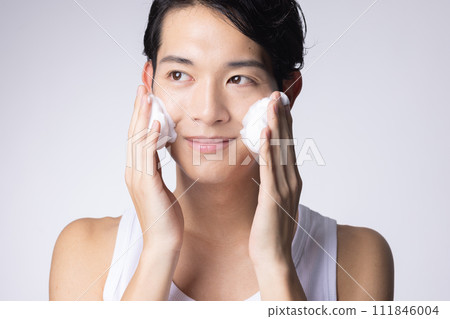Portrait of a man washing his face and doing skin care on a white background 111846004