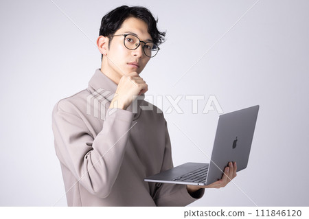 一名戴眼鏡的年輕人操作電腦的圖片 一名戴眼鏡的年輕人操作電腦的圖片 111846120
