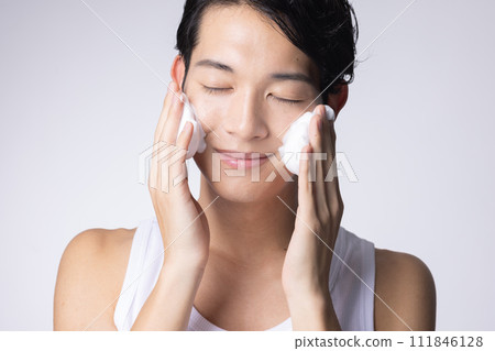 Portrait of a man washing his face and doing skin care on a white background 111846128