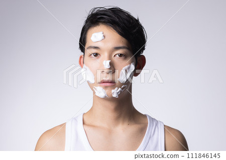 Portrait of a man washing his face and doing skin care on a white background 111846145