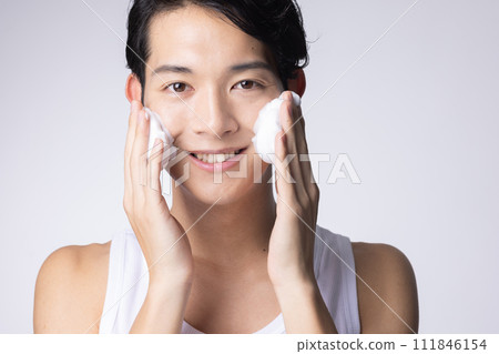 Portrait of a man washing his face and doing skin care on a white background Portrait of a man washing his face and doing skin care on a white background 111846154