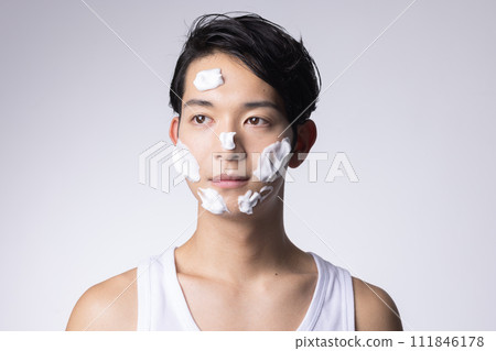 Portrait of a man washing his face and doing skin care on a white background 111846178