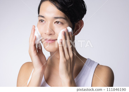 Portrait of a man washing his face and doing skin care on a white background 111846190