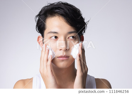 Portrait of a man washing his face and doing skin care on a white background Portrait of a man washing his face and doing skin care on a white background 111846256