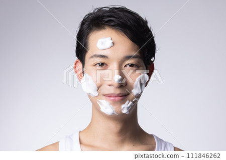 Portrait of a man washing his face and doing skin care on a white background 111846262