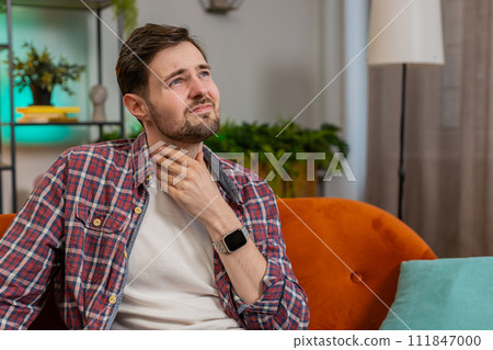 Upset man holds hands over sore throat painful neck frowning thyroid disorders tonsils inflammation Upset man holds hands over sore throat painful neck frowning thyroid disorders tonsils inflammation 111847000