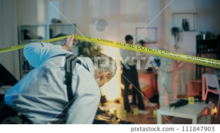 A detective is entering the crime scene to join his colleagues in the evidence collection process A detective is entering the crime scene to join his colleagues in the evidence collection process 111847903