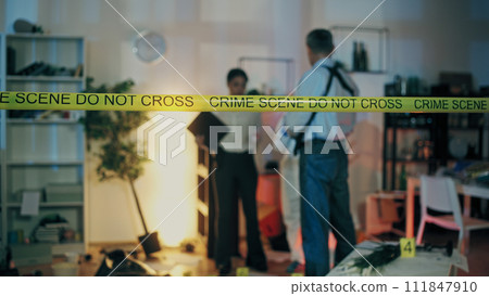 Detectives examine evidence while forensic experts work at the crime scene in the apartment Detectives examine evidence while forensic experts work at the crime scene in the apartment 111847910