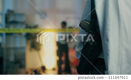 A detective with a gun in a holster is visiting the crime scene, part of a murder investigation, seen from the back A detective with a gun in a holster is visiting the crime scene, part of a murder investigation, seen from the back 111847911