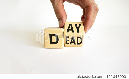 Day of the dead symbol. Businessman turns a wooden cube and changes the word 'Dead' to 'Day'. Beautiful white table, white background, copy space. Day of the dead concept. 111848000