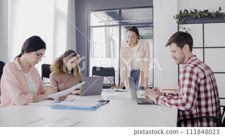 PR specialist talking to colleagues during meeting, teamwork in office, business PR specialist talking to colleagues during meeting, teamwork in office, business 111848023