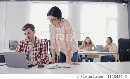 Female supervisor checking male employee's project on laptop, work in business office 111848043