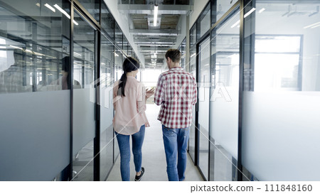 Marketing specialists discussing sales report, walking in office corridor, team 111848160