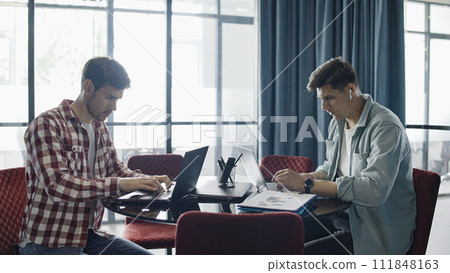 Two programmers working on laptops in office, developing strategy of startup 111848163