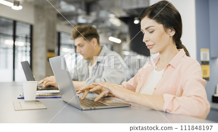 IT specialists typing on laptops, working in office together, modern technology 111848197