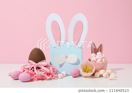 Blue gift box with rabbit ears and chocolate eggs Blue gift box with rabbit ears and chocolate eggs 111848523