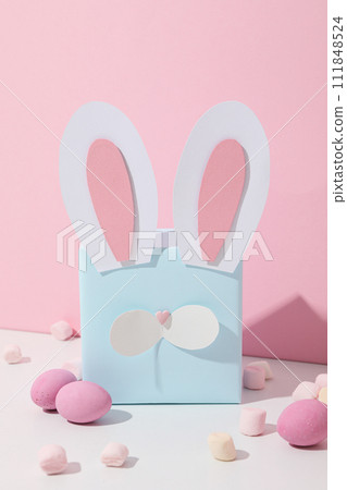 Blue gift box with rabbit ears and chocolate eggs Blue gift box with rabbit ears and chocolate eggs 111848524
