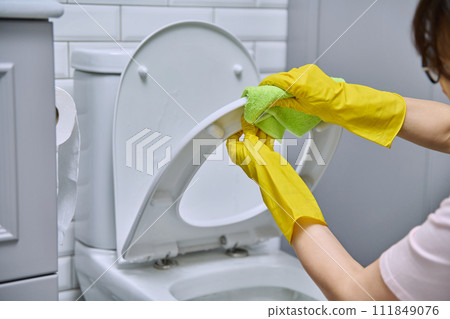 Close-up hands in protective gloves cleaning toilet in bathroom Close-up hands in protective gloves cleaning toilet in bathroom 111849076