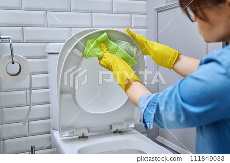 Close-up hands in protective gloves cleaning toilet in bathroom 111849088