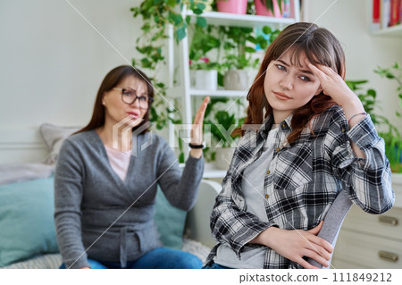Conflict between mother and teen daughter, offended teenage girl sitting with back 111849212