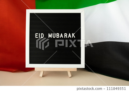 Message text EID MUBARAK - happy holidays waving UAE flag on background concept. Greeting card advertisement. Commemoration Day Muslim Ramadan Blessed holy month public holiday Message text EID MUBARAK - happy holidays waving UAE flag on background concept. Greeting card advertisement. Commemoration Day Muslim Ramadan Blessed holy month public holiday 111849351