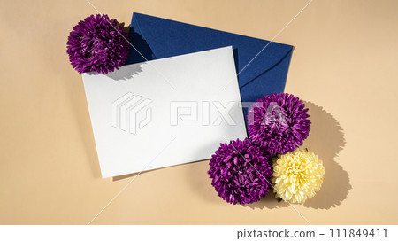 Composition with empty paper note and envelope beautiful spring violet and white flowers on beige background. Mockup card invitation greeting card postcard copy space template Composition with empty paper note and envelope beautiful spring violet and white flowers on beige background. Mockup card invitation greeting card postcard copy space template 111849411