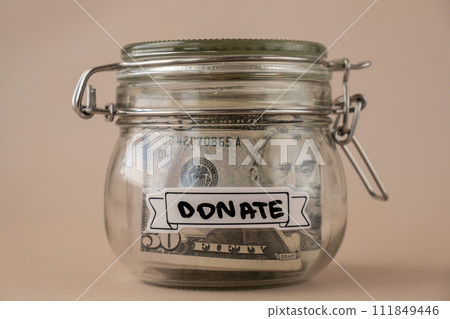 Glass jar full of American currency dollars cash banknote with text DONATE. Preparation saving money. Moderate consumption and economy 111849446