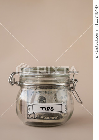 Glass jar full of American currency dollars cash banknote with text TIPS. Preparation saving money. Moderate consumption and economy 111849447