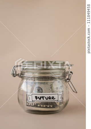 Glass jar full of American currency dollars cash banknote with text FUTURE. Preparation saving money. Moderate consumption and economy 111849458
