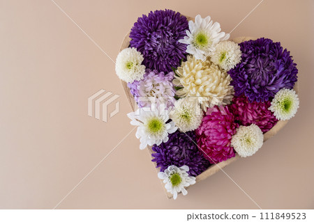 Colorful mixed flowers in shape of heart on beige background. Concept of love and valentines day, weeding, anniversary. Postcard greeting card template. Flat lay minimalistic 111849523